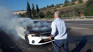 ר', ראש השב"כ המיועד, מסייע בכיבוי רכב העולה באש בדרכו לוועדת גולדברג