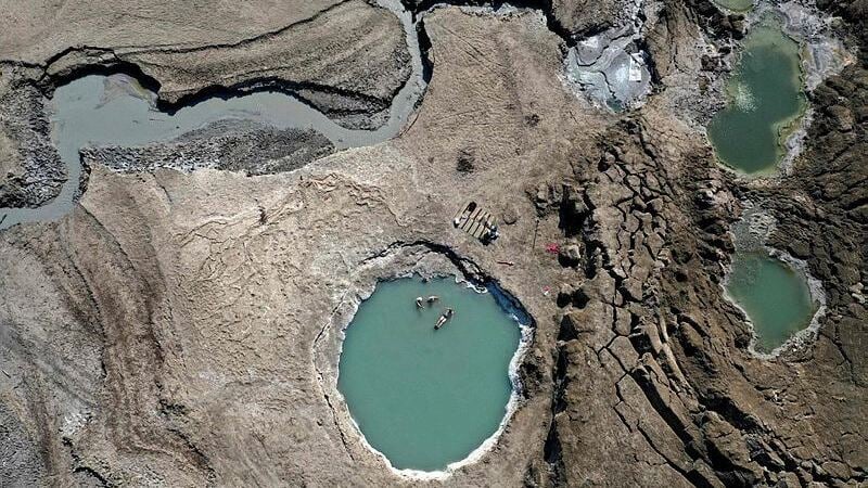 A sinkhole filled with water becomes paddle pool for visitors to the Dead Sea shore (Photo: AFP) אנשים בתוך בולען שהתמלא במים ליד ים המלח