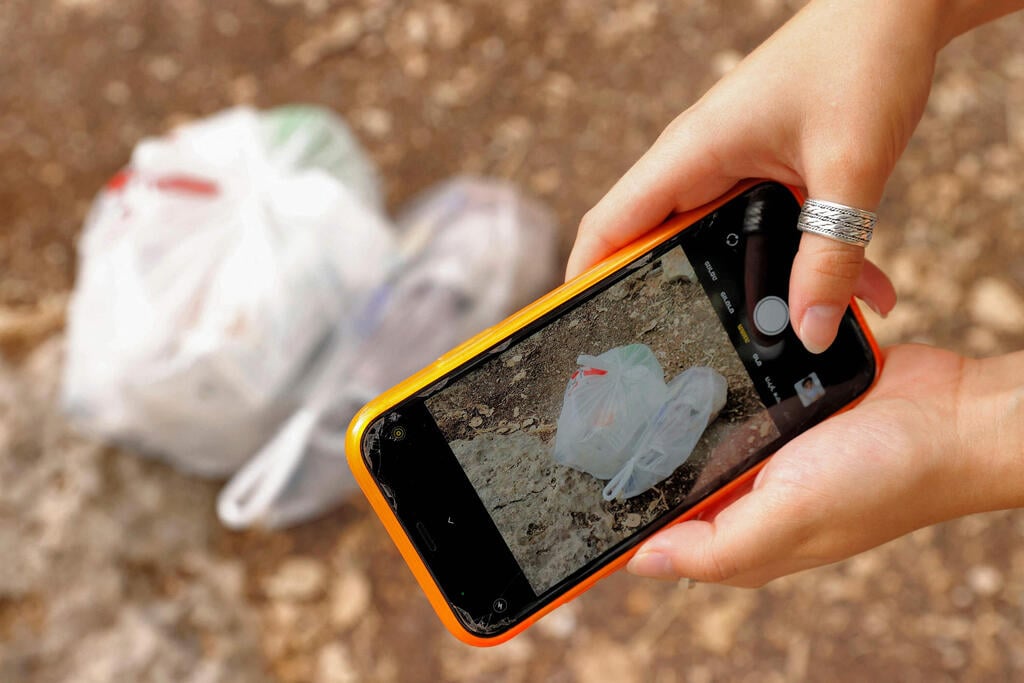 Elishya Ben Meir taking a photo of the garbage she collected through Clean Coin (Photo: AFP) Elishya Ben Meir taking a photo of the garbage she collected