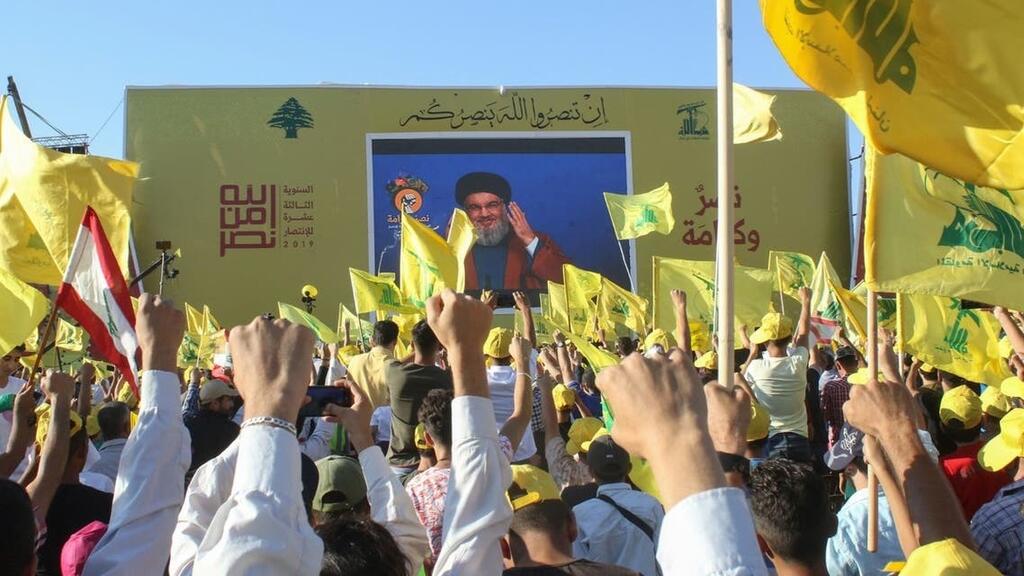 Supporters of the Lebanese Shiite militant movement Hezbollah wave th group's flag during a commemoration marking the 13th anniversary of the end of the 2006 war with Israel in the southern Lebanese