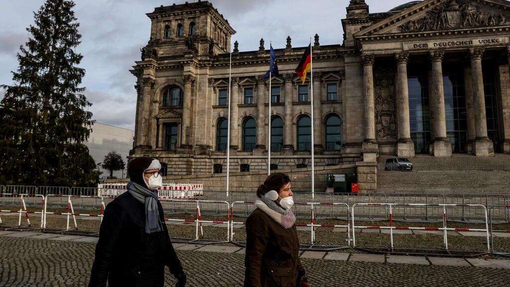 People walk in Berlin wearing masks (Photo: EPA) עוטים מסכות ליד הפרלמנט הגרמני בברלין