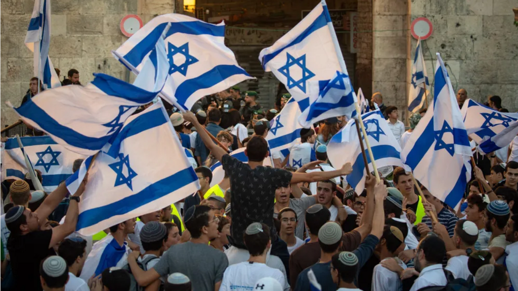 Activists hold Israeli flags during the March of Flags at Damascus Gate in Jerusalem's Old City, June 15, 2021 (Photo: Flash90) Israelis hold Israeli flags and dance during the March of Flags at Damascus Gate in Jerusalem's Old City, June 15, 2021
