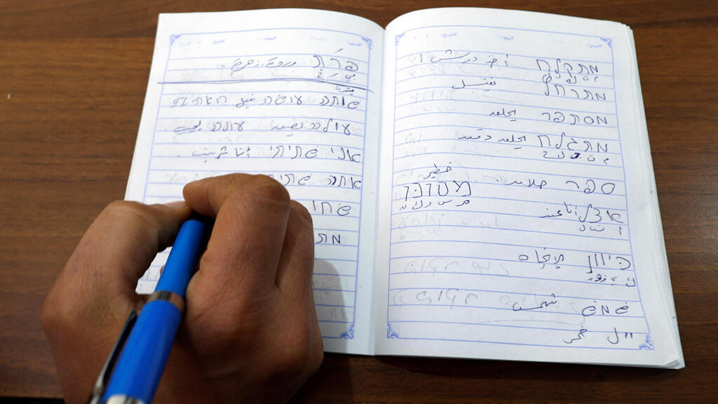 A young Palestinian man writes in Hebrew during a class at Nafha Language Center, in Khan Younis in the southern Gaza Strip 