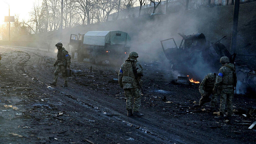 Ukrainian service members collect unexploded shells after a fighting with Russian raiding group in the Ukrainian capital of Kyiv in the morning of February 26, 2022 