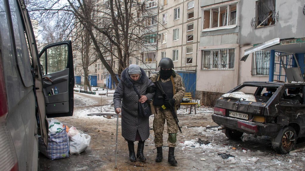 A Ukrainian soldier assists an elderly woman on the streets of Kharkiv on Tuesday (Photo: EPA) חייל אוקראיני עוזר ל קשישה לעזוב בניין מבנה מגורים שנהרס הרס הפגזות ב חרקוב אוקראינה צבא מלחמה באירופה