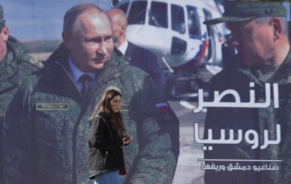 A woman passes a billboard showing Russian President Vladimir Putin in Damascus, Syria 