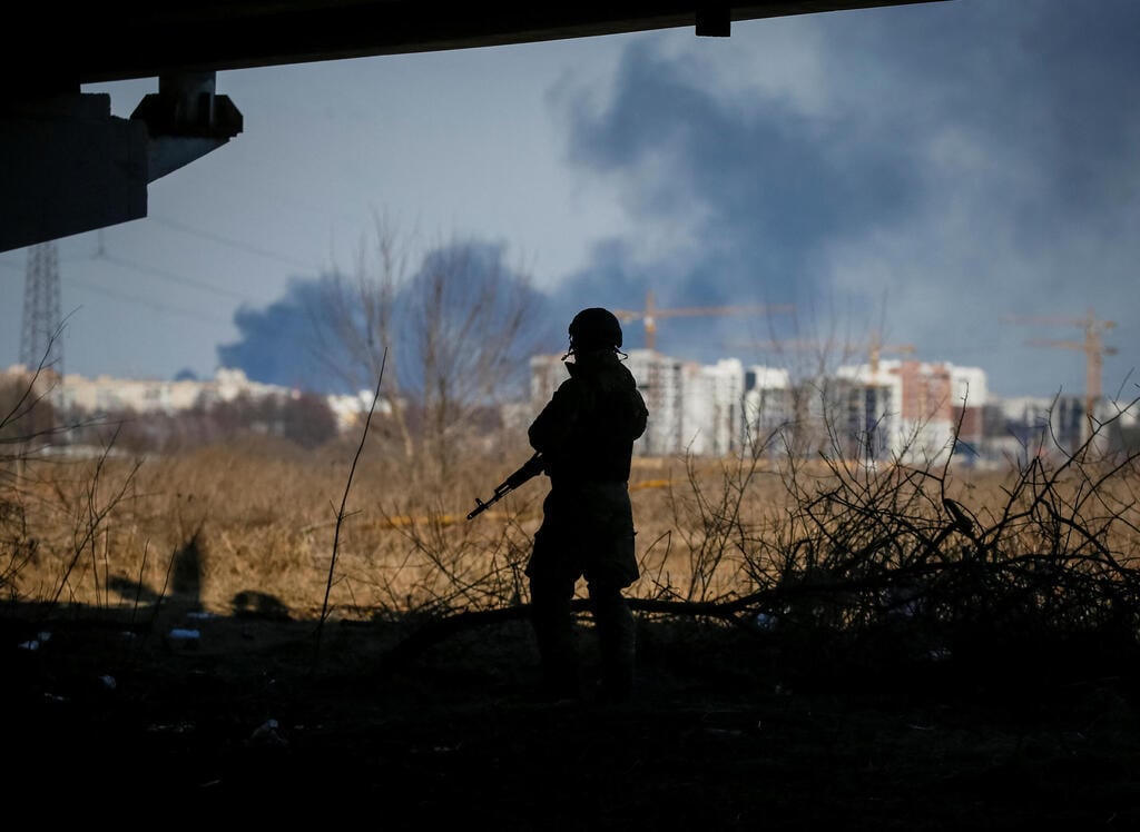 Ukrainian soldier looks on as smoke billows, in Irpin, Ukraine (Photo: Reuters) חייל אוקראיני באירפין