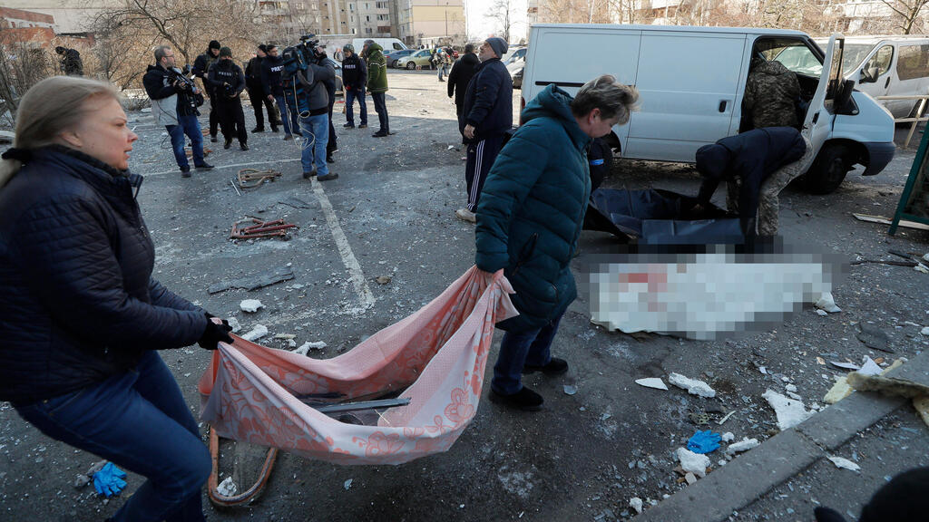 Ukrainians rush to remove the body of a local woman killed in a Russian bombing off the street in Kyiv on Thursday (Photo: EPA) קרובי משפחה של אישה שנהרגה בפגיעת הטיל מגיבים כשאנשי רפואה מפנים את גופתה