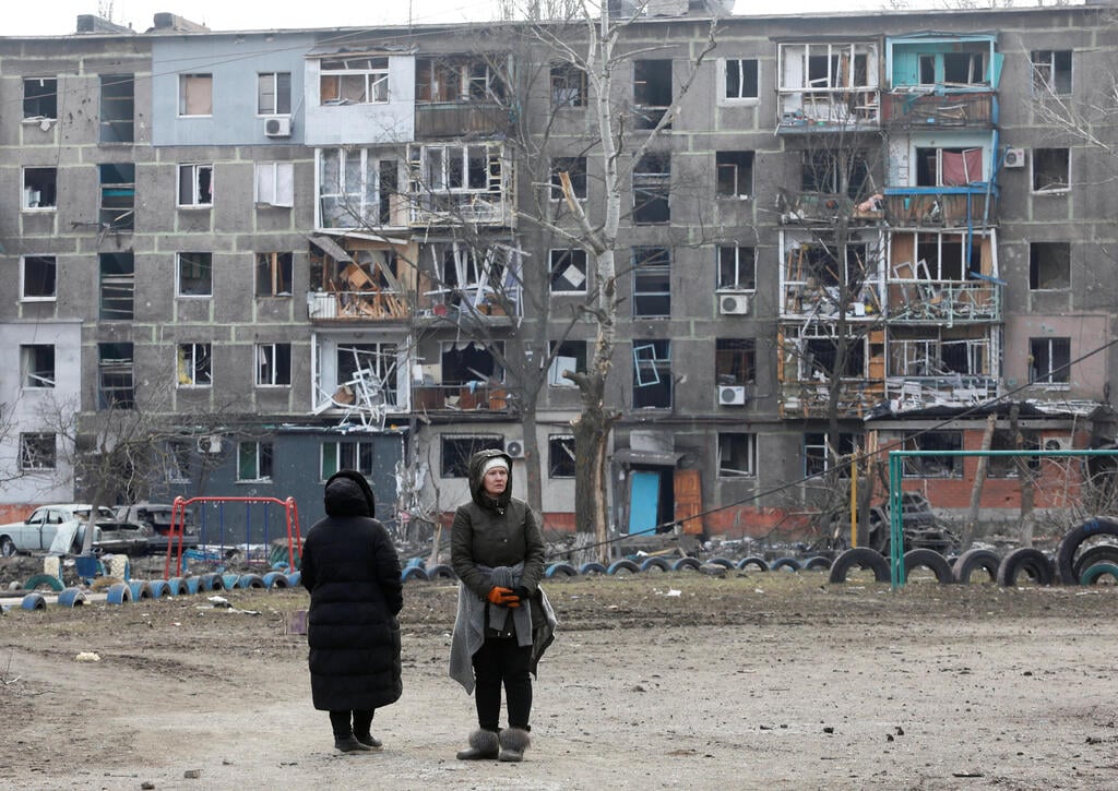 Civilians standing against buildings damaged in Russian shelling, in Mariupol, Ukraine (Photo: Reuters) מריופול תושבים בין ההריסות
