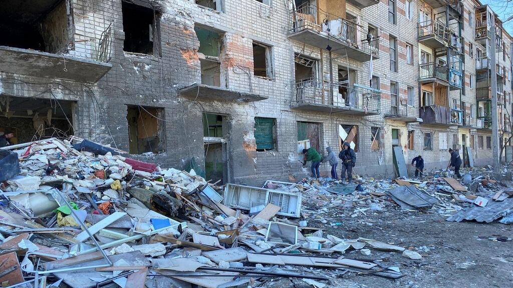 Municipal workers and volunteers remove debris of a damaged residential building, as Russia's attack on Ukraine continues, in Kharkiv