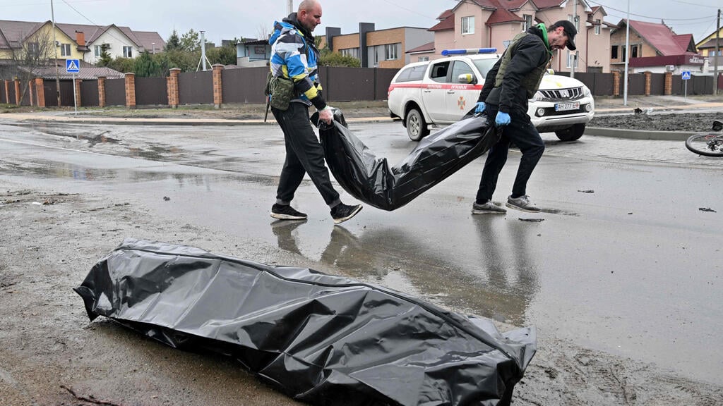 Bodies being taken off a street in the Ukrainian city of Bucha (Photo: AFP) פינוי גופות בבוצ'ה