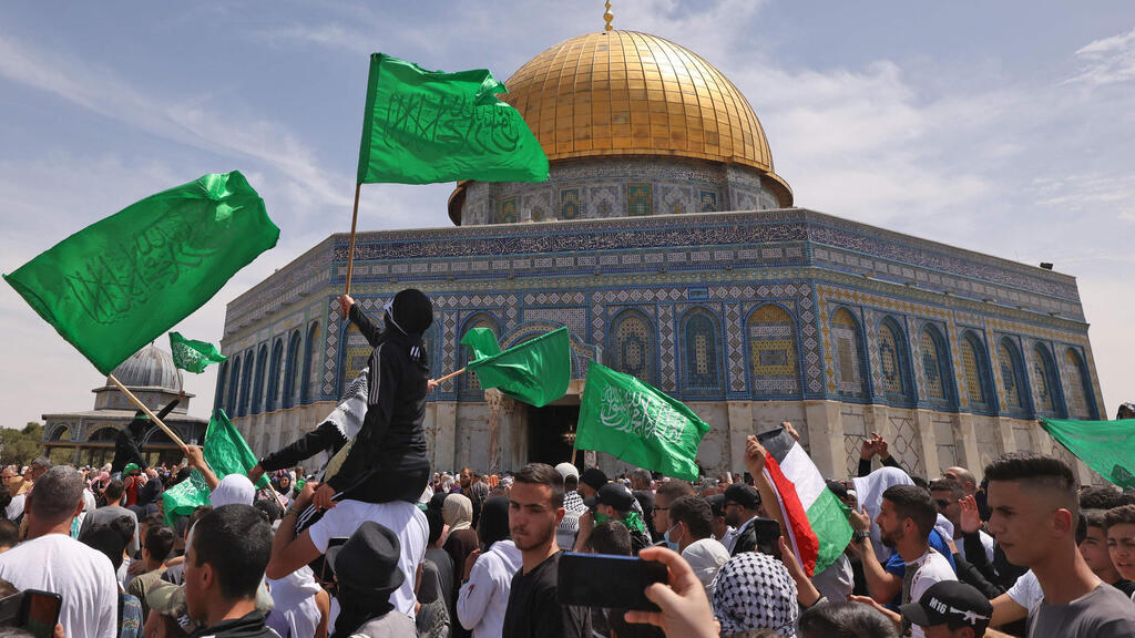 Palestinians on Temple Mount wave the flags of the terrorist group Hamas (Photo: AFP) פלסטינים מנופפים בדגלי פלסטין וחמאס בהר הבית
