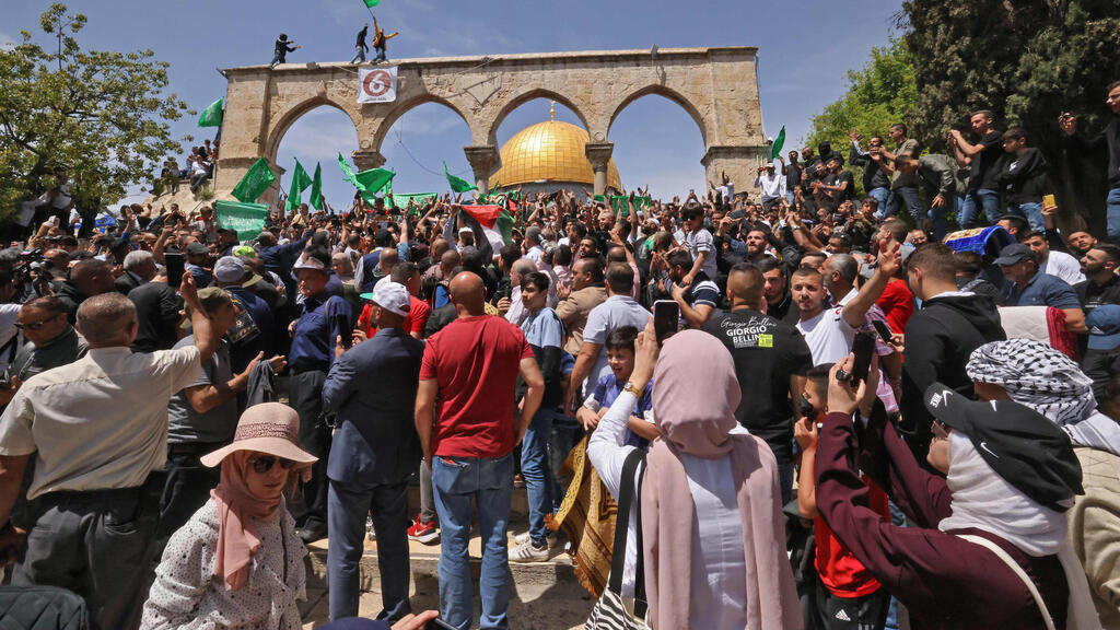 Muslim worshipers fly Palestinian, Hamas flags on Al Aqsa Mosque compound (Photo: AFP) פלסטינים מנופפים בדגלי פלסטין וחמאס בהר הבית