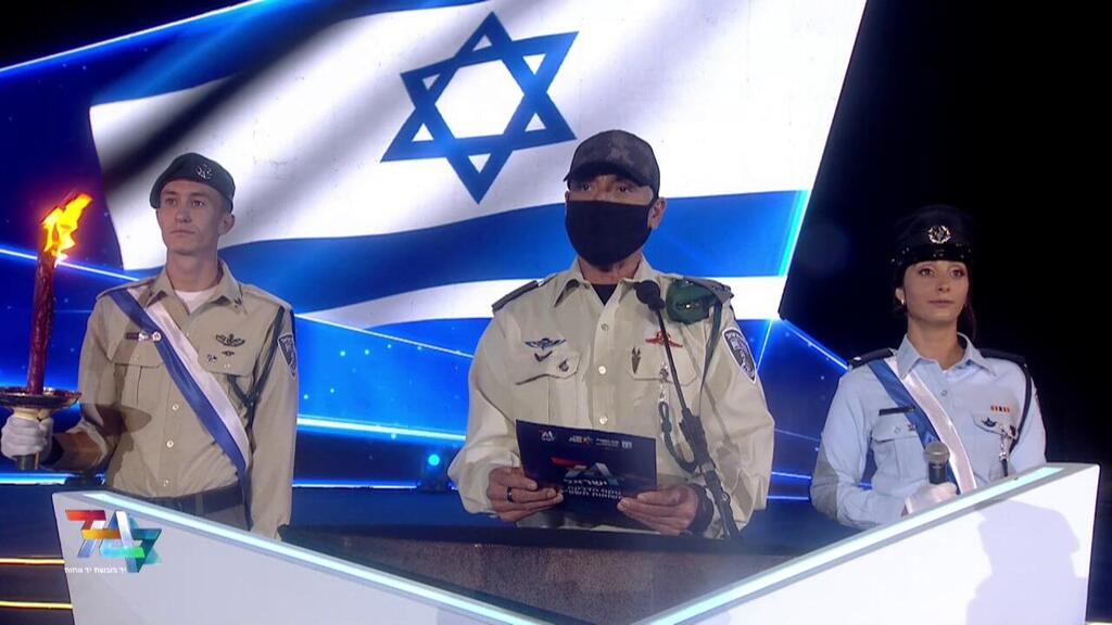 מפקד הימ"מ מדליק משואה בטקס, עם מסכה וכובע (צילום : אולפני הרצליה, מרכז ההסברה המטה לאירועים וטקסים ממלכתיים) טקס הדלקת המשואות בהר הרצל