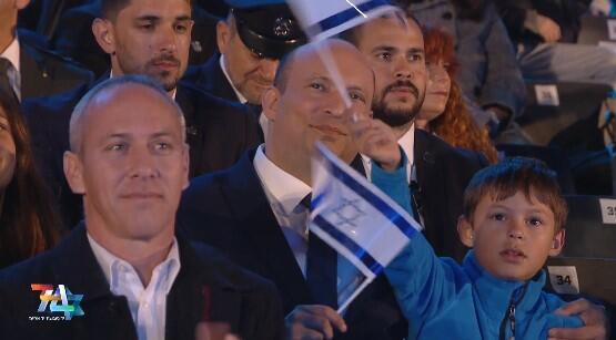 בנט יחד עם בנו, אותו נצפה בתום הטקס נושא על כתפיו (צילום : אולפני הרצליה, מרכז ההסברה המטה לאירועים וטקסים ממלכתיים) טקס הדלקת המשואות בהר הרצל