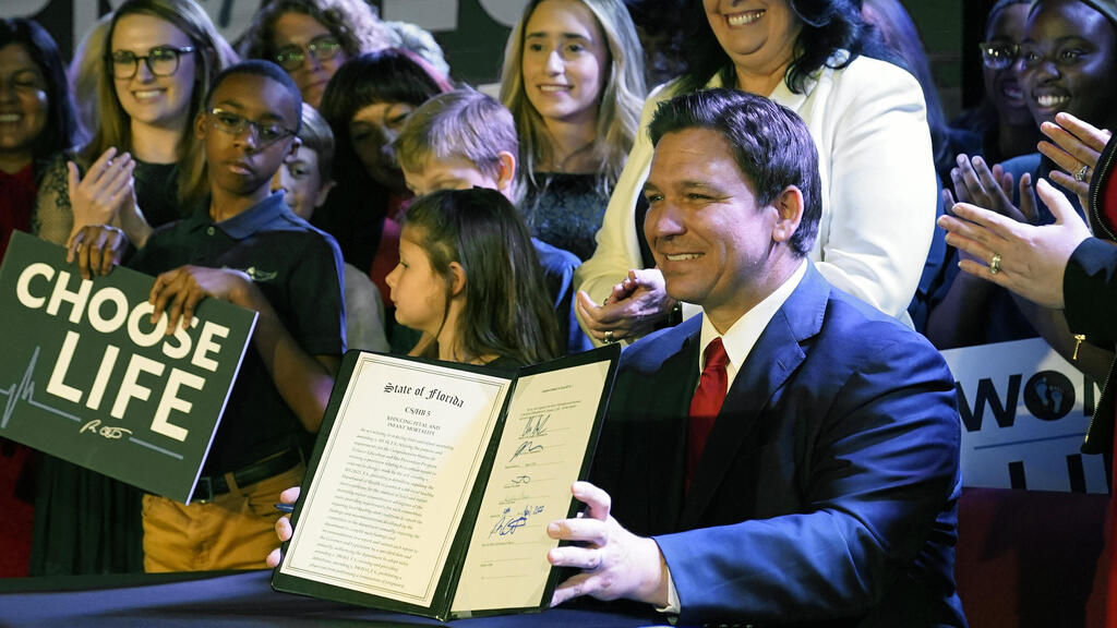 Florida Gov. Ron DeSantis holds up a 15-week abortion ban law after signing it on April 14, 2022, in Kissimmee, Fla