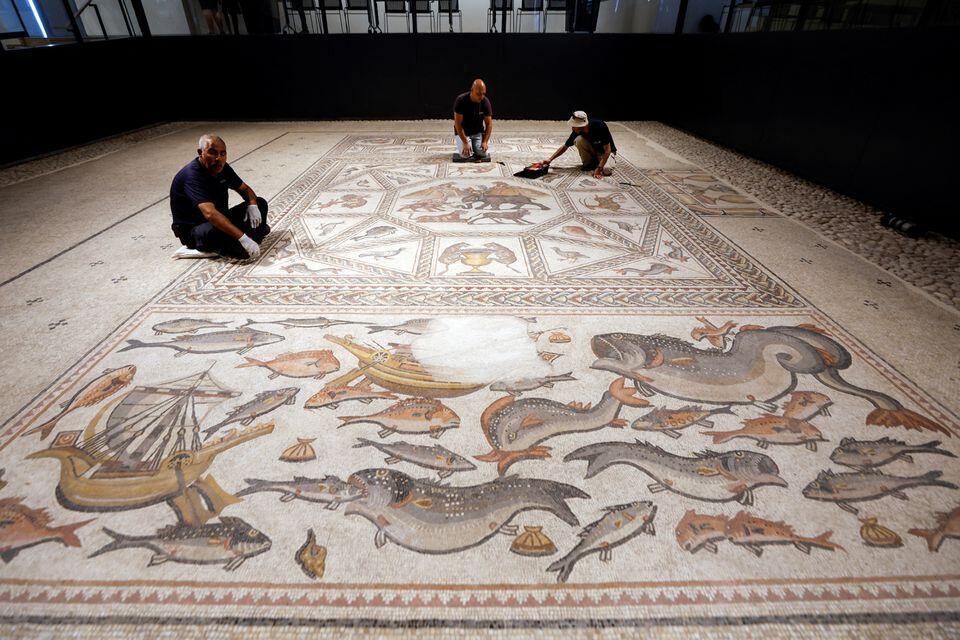 Workers clean a restored Roman-era mosaic after it was put on display at its original site in Lod 