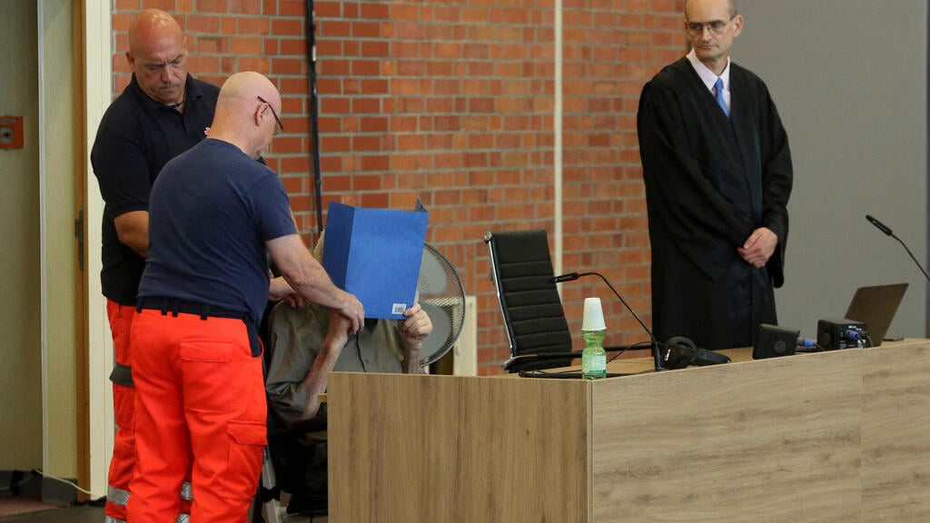 Defense lawyer Stefan Waterkamp (R) attends the sentencing hearing of the trial of his client former Nazi concentration camp guard Josef Schuetz (2nd R) as he is installed by helpers of the German Red Cross (Photo: AFP) Defense lawyer Stefan Waterkamp (R) attends the sentencing hearing of the trial of his client former Nazi concentration camp guard Josef Schuetz (2nd R)) as he is installed by helpers of the German Red Cross