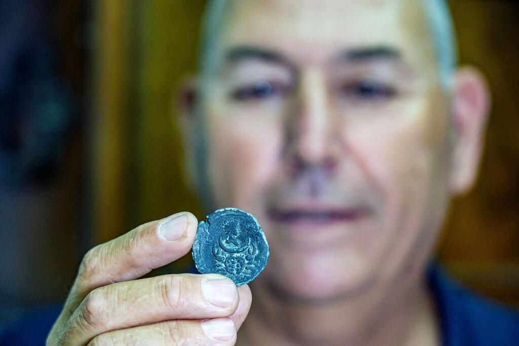 קובי שרביט, מנהל היחידה הימית של רשות העתיקות, עם המטבע שנמצא בסקר בימי