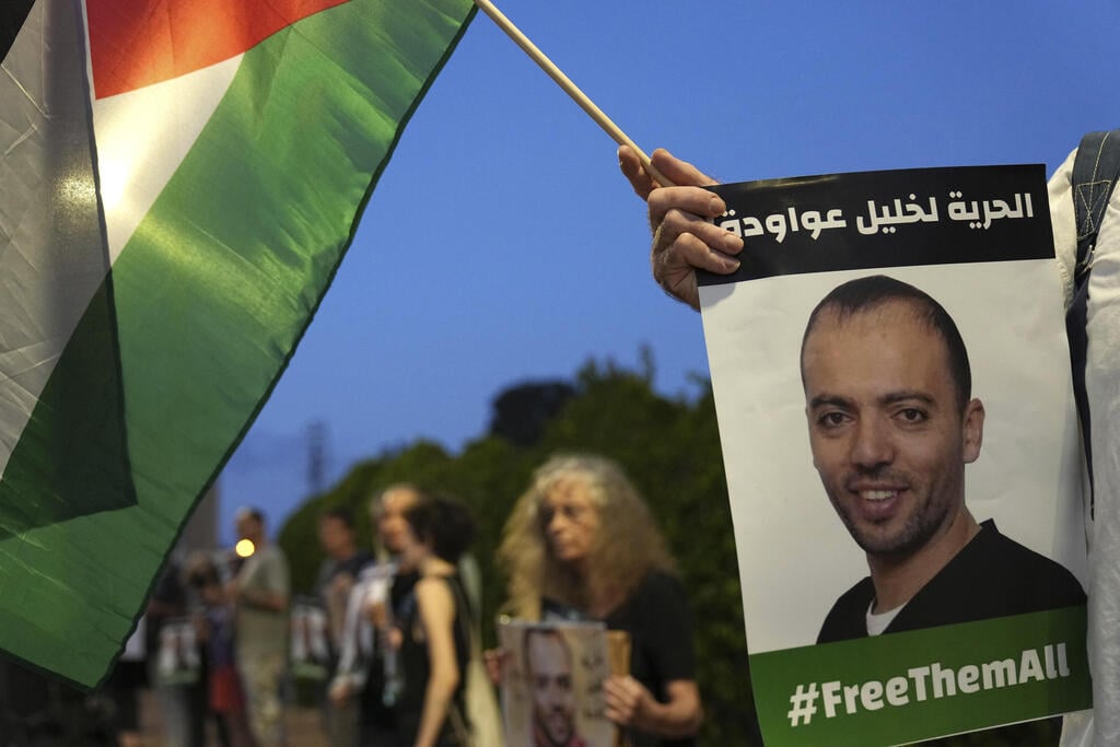 Protesters gather outside hospital where Khalil Awawdeh, on months-long hunger strike is treated (Photo: AP) Protesters gather outside hospital where Khalil Awawdeh, pictured in placards, a Palestinian prisoner in Israel is on hunger strike, in Be'er Yaakov, Aug. 13, 2022