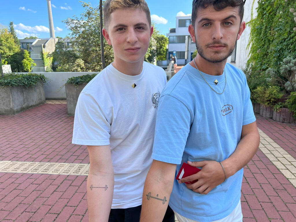 נכדיה של אילנה רומנו וקעקוע המשקולות (צילום: זאב אברהמי) אילנה רומנו ונכדיה בזירת טבח הספורטאים במינכן