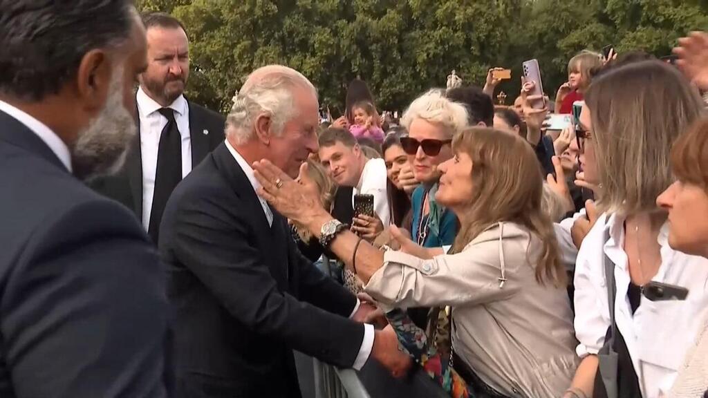 המלך צ'רלס נשיקה לאישה בקהל ליד ארמון בקינגהאם לונדון בריטניה
