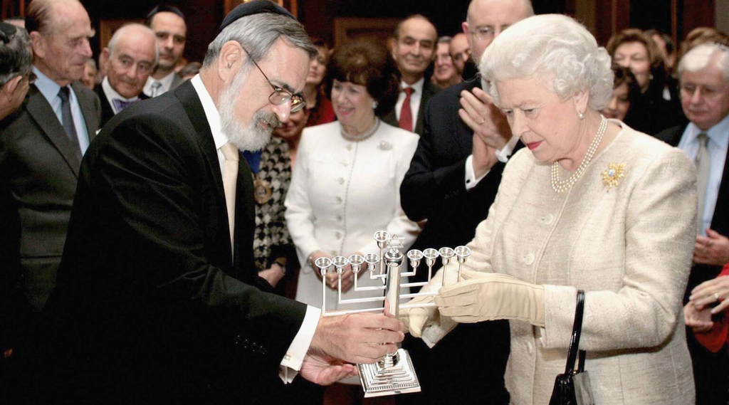 The late British Chief Rabbi Jonathan Sacks gives the queen a menorah at a reception at St. James’ Palace in London to mark the 350th anniversary of the re-establishment of the Jewish community in Britain, Nov. 28, 2006 