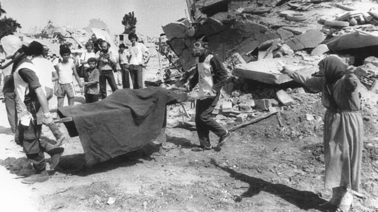 In this file photo taken on September 19, 1982, a Palestinian woman cries while civil defense workers carry the body of her relative 