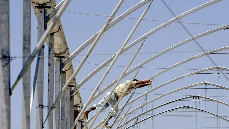 A Palestinian worker unbolts a metal framework as he and others help dismantle Israeli owned greenhouses near the New Pe'at Sade settlement of the Gush Katif settlement bloc in southern Gaza Strip, July 29, 2005 