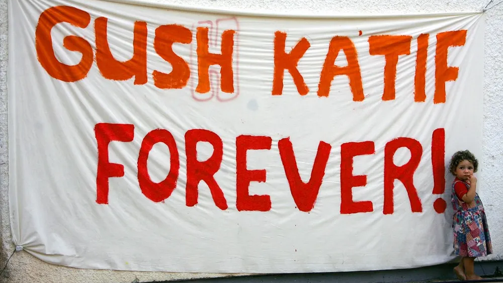 A young child stands next to a banner with the inscription "Gush Katif Forever" at the Gaza Strip settlement of Nezer Hazani in the Gush Katif bloc, Gaza Strip, August 17, 2005 
