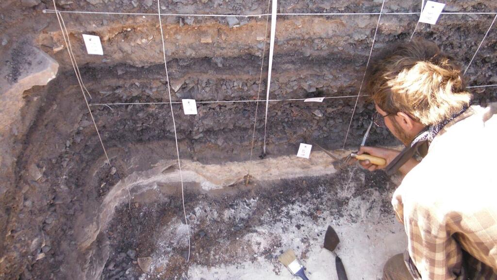 Investigating a pile of industrial waste mixed with charcoal (Photo: Courtesy of Hai Ashkenazi, courtesy of the Central Timna Valley Project) בדיקת ערימת פסולת הפקת נחושת עם פחמי עץ ששמשו לבעירת הכבשנים, גבעת העבדים, בקעת תמנע