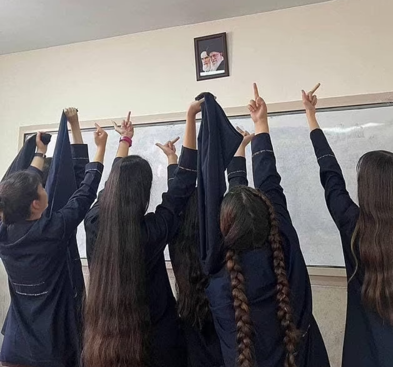 תלמידות תיכון מפנות אצבע משולשת לתמונותיהם של המנהיג העליון עלי חמניאי וקודמו רוחאללה חומייני, בתמונה שהופצה בשיאה של "מחאת החיג'אב" תלמידות תיכון ב איראן מפנות אצבע משולשת לתמונותיהם של המנהיג העליון עלי חמניאי וקודמו רוחאללה חומייני בכיתה בבית ספר תמונה שהופצה ברשתות החברתיות ופורסמה גם בגרדיאן הבריטי