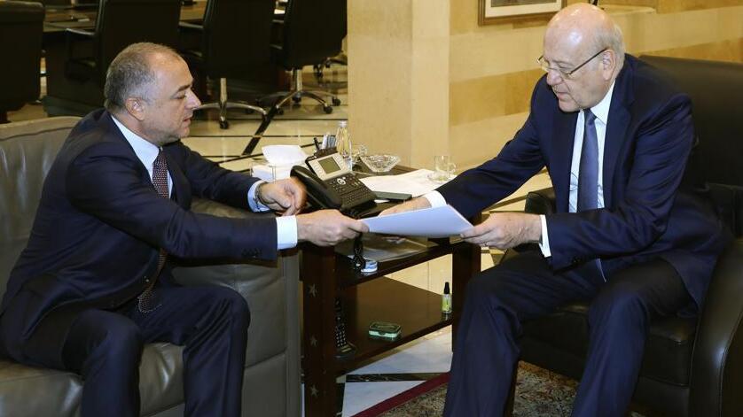 Lebanese Prime Minister Najib Makati, right, receives the final draft of the maritime border agreement between Lebanon and Israel from his deputy Elias Bou Saab who leads the Lebanese negotiating team, in Beirut, Lebanon, Tuesday, Oct. 11, 2022 