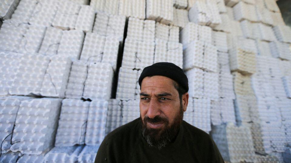 A Palestinian worker sits in front of newly made egg trays, manufactured from recycled paper waste, in Khan Younis, in the southern Gaza Strip, November 10, 2022 
