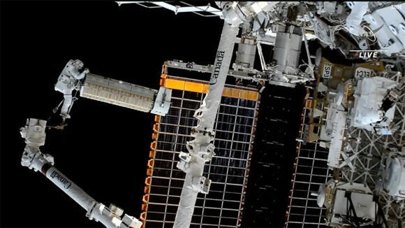 להבטיח אספקת חשמל יציבה. האסטרונאוט ג'וש קסדה ניצב בקצה הזרוע הרובוטית של התחנה במהלך הצבתם של הלוחות הסולריים החדשים