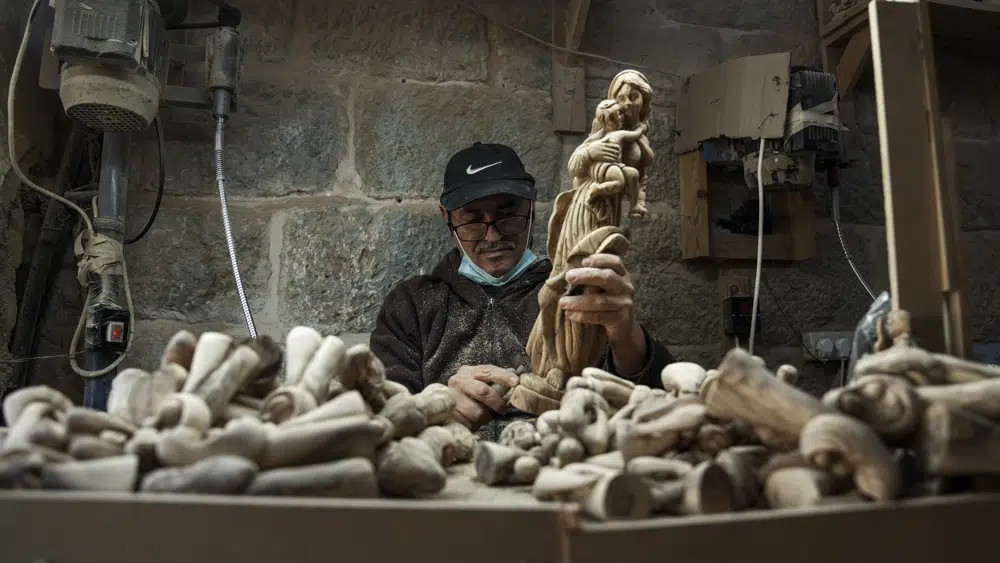 A Palestinian craftsman carves a figurine of the Virgin Mary and baby Jesus, in the West Bank town of Bethlehem, at the beginning of the Christmas season, Saturday, Dec. 3, 2022 