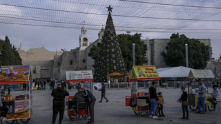 Palestinian vendors wait for clients next to the Christmas tree in Manger Square, adjacent to the Church of the Nativity, traditionally believed by Christians to be the birthplace of Jesus Christ, ahead of Christmas, in the West Bank city of Bethlehem, Monday, Dec. 5, 2022 