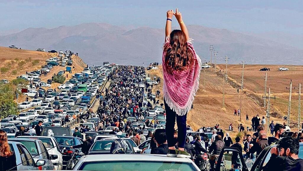 מפגינה צעירה על רקע אחד ממצעדי המחאה באיראן