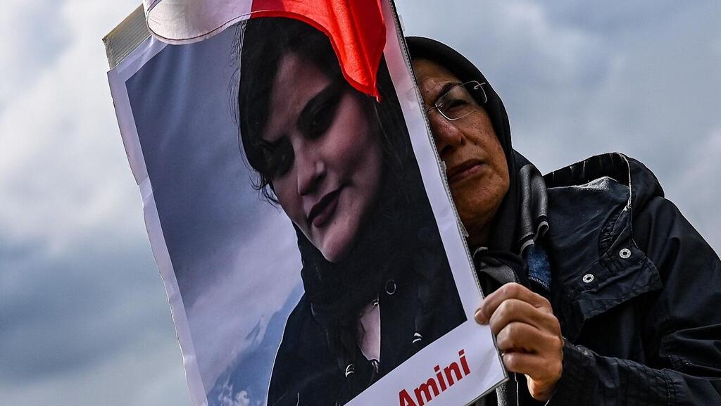 A protester against Iran's modesty laws holds a photo of Mahsa Amini (Photo: EPA) מפגינה נושאת את תמונתה של מהסא אמיני