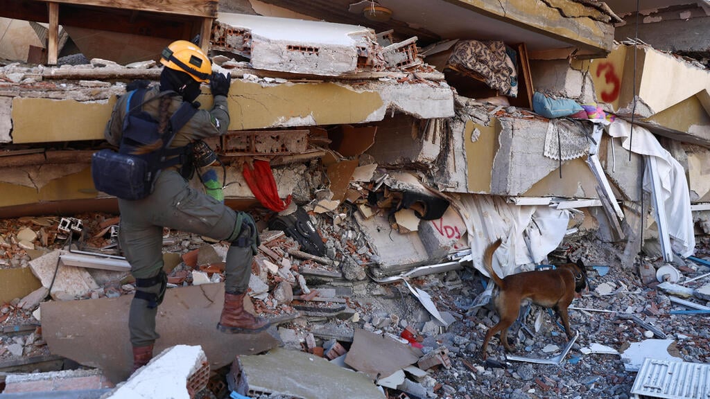 Israeli rescue worker searching for survivors in Turkey (Photo: Reuters) כלב חילוץ בפעולה, ולידו חברת המשלחת הישרלאית