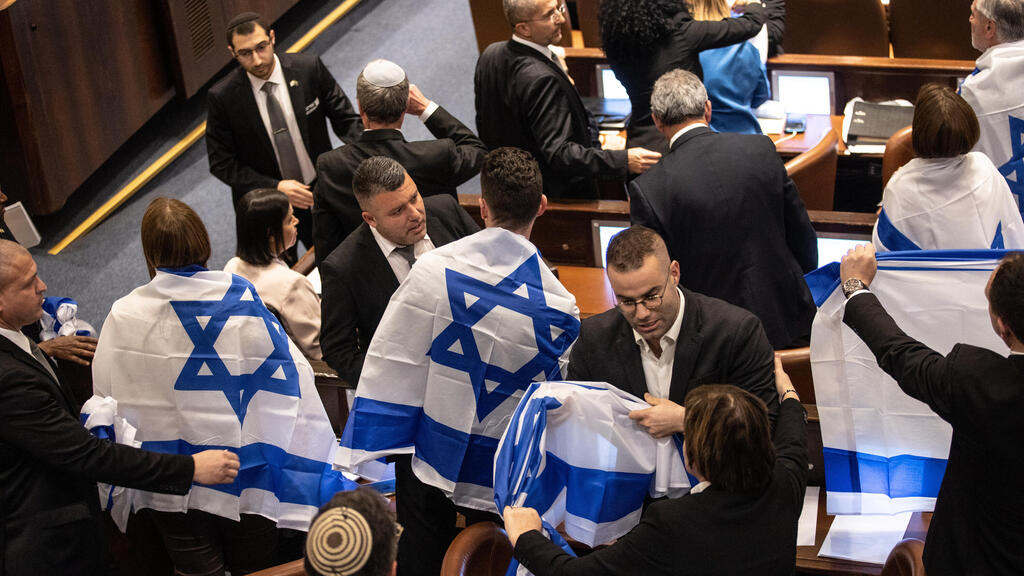 חברי האופוזיציה מתעטפים בדגלים, בניגוד לכללי המליאה (צילום: אלכס קולומויסקי) חברי האופוזיציה מתעטפים בדגלי ישראל לקראת ההצבעה בקריאה ראשונה על חוקי הרפורמה המשפטית