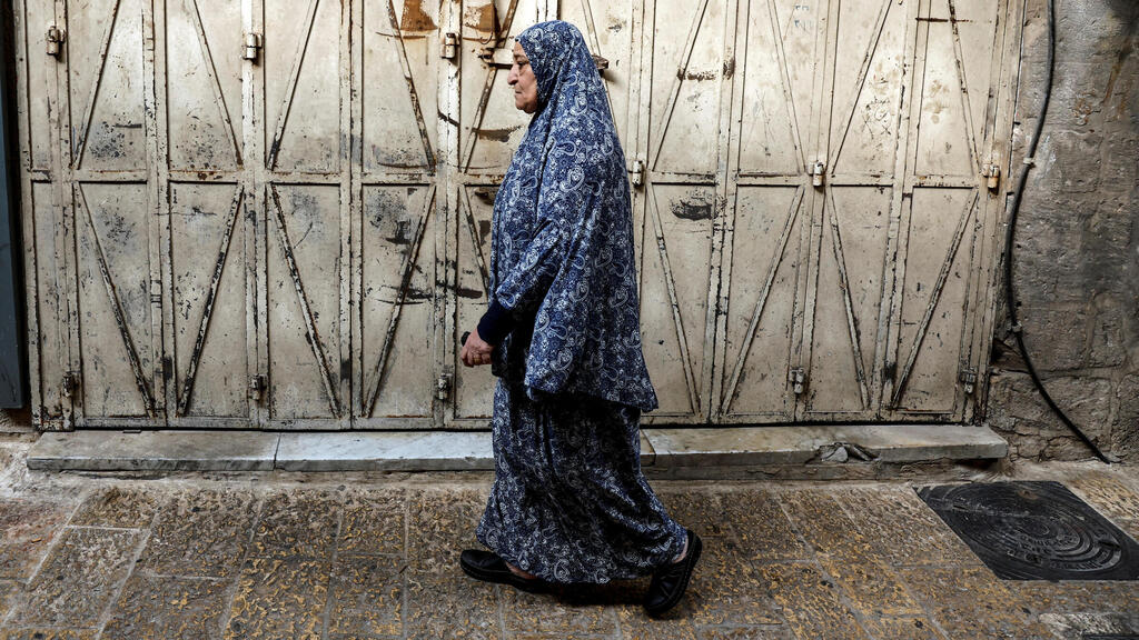 Woman walks by shops closed in general West Bank strike 