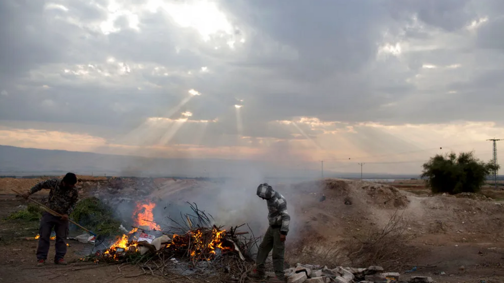 Palestinian farmers burn waste just outside the West Bank settlement of Petsael 
