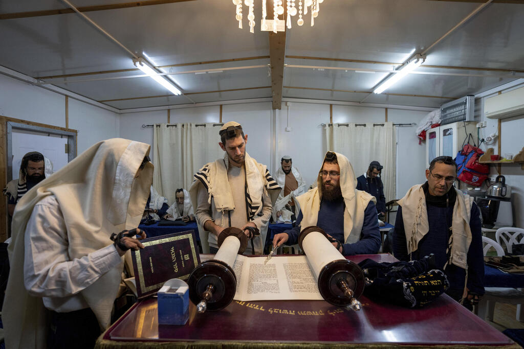 Jewish settlers participate in a morning prayer at their synagogue in the West Bank outpost of Beit Hogla