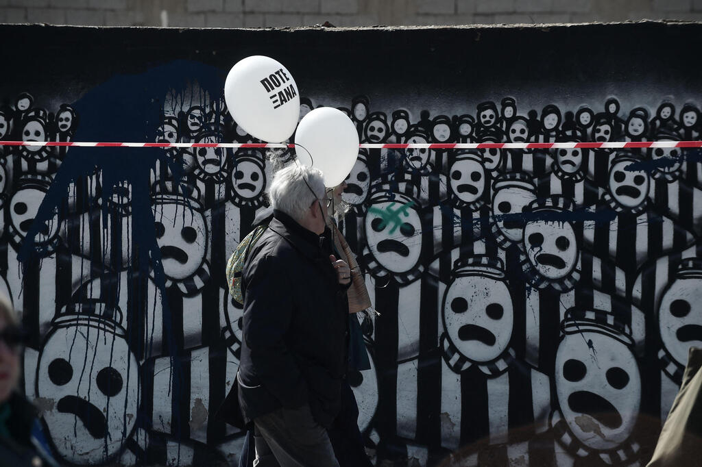 Participants hold balloons reading "Never Again" as they walk towards the old railway station in Thessaloniki