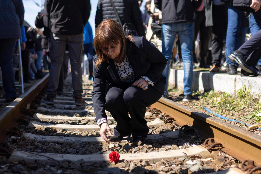 Greek President Katerina Sakellaropoulou leaves a carnation on the train tracks in Thessaloniki