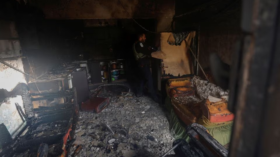 An Israeli policeman checks the damage in a Palestinian house which Palestinians say was attacked by Israeli settlers near Ramallah in the Israeli-occupied West Bank, March 26, 2023 
