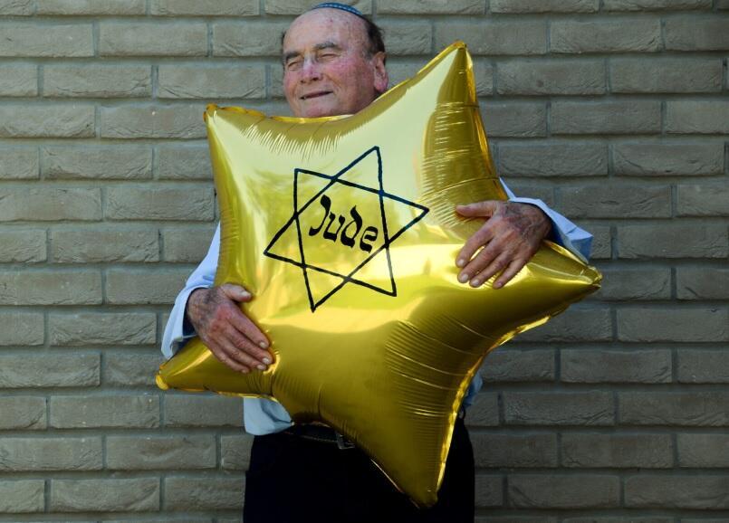 Dugo Leitner, a survivor of Auschwitz-Birkenau, holds a balloon shaped like the Jewish star that the Nazis forced Jews to wear 