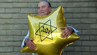 Dugo Leitner, a survivor of Auschwitz-Birkenau, holds a balloon shaped like the Jewish star that the Nazis forced Jews to wear 