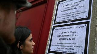 Person read posters bearing names of Jewish children deported by Nazis, displayed on the building where they lived, in Paris, France 